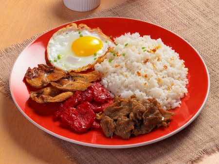 A dish of Tapa King Royal Meal with fried egg, classic tapa, fried rice, crispy danggit, tocino, and atchara art directed and photographed by Bluethumb