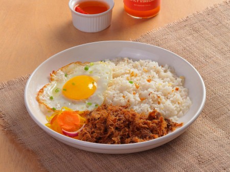 a dish of Crispy-shredded Tapa King with fried egg, tapa, fried rice, and atchara