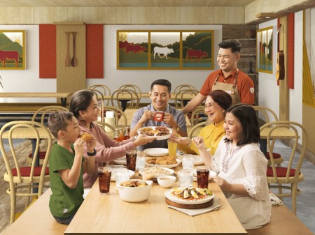 Thematic photo of a family enjoying a Tapa King feast served by a waiter in new uniform art directed and photographed by Bluethumb